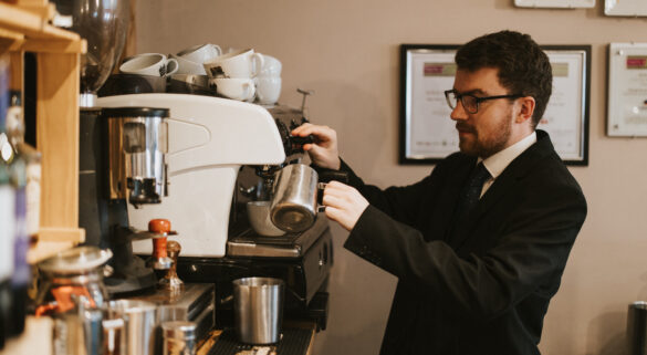 A member of the team who has joined as an apprentice and is making a cup of coffee